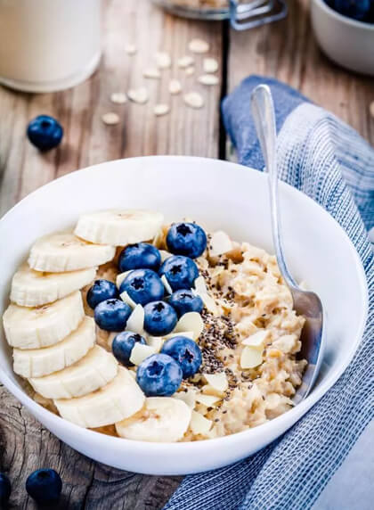 A bowl of oats topped with blueberries, banana, and seeds.